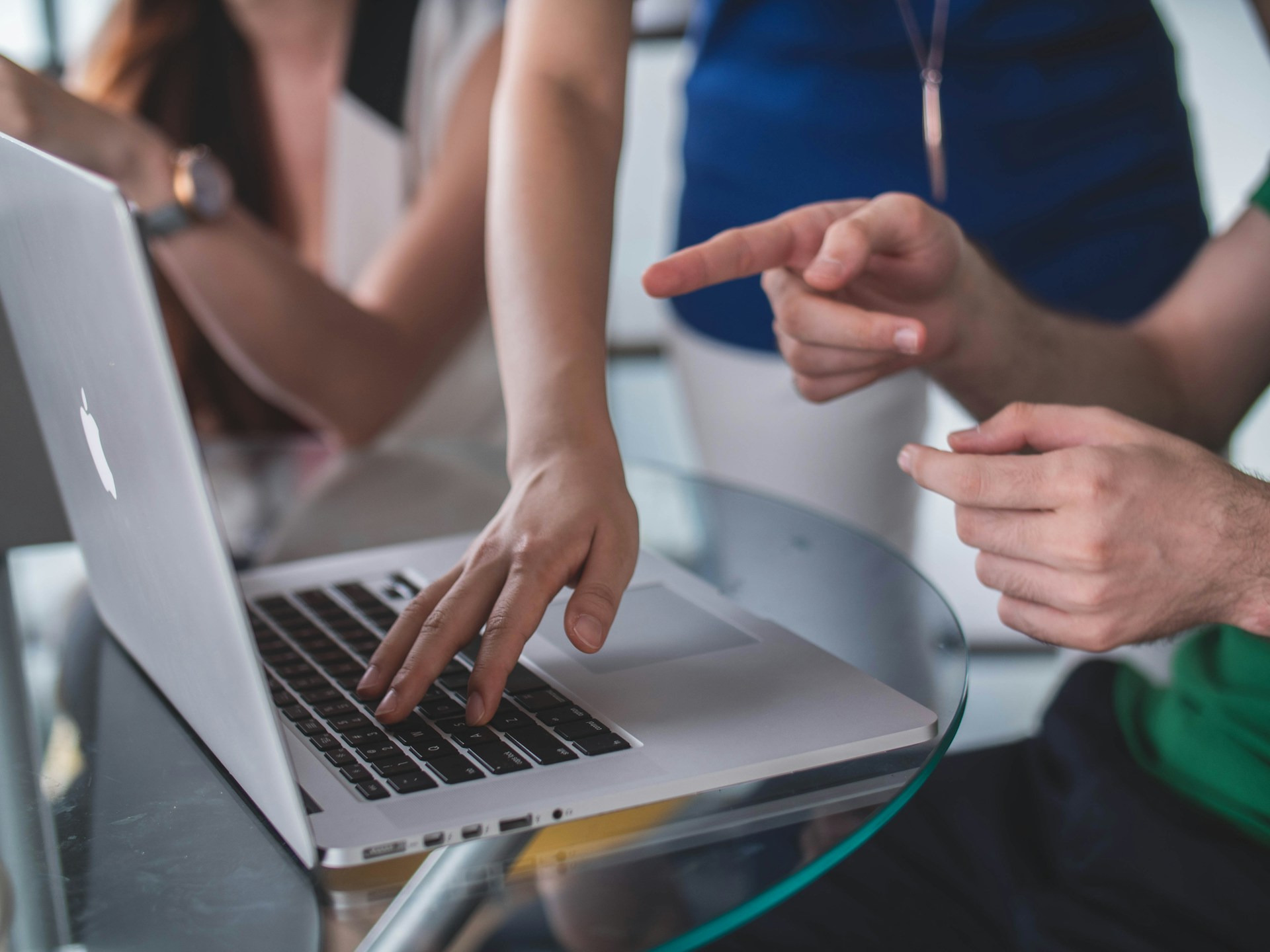 A digital marketing agency in Cape Town working together on a macbook around a glass table.