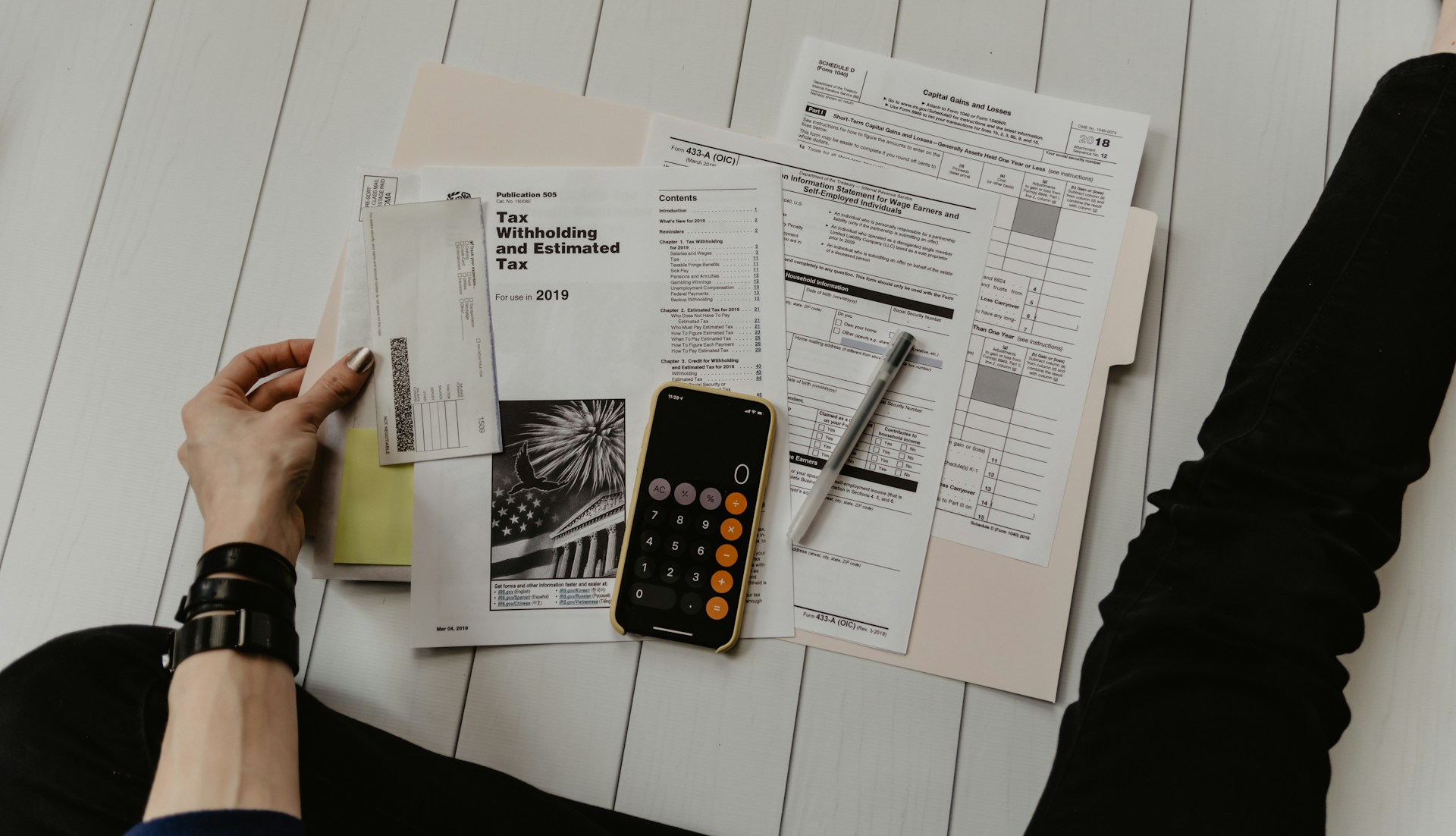 A person doing accounting on paper with a calculator and pen to represent accounting software